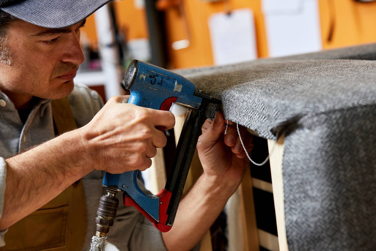 A worker applying upholstery fabric to an armchair in a workshop near Amissville, VA